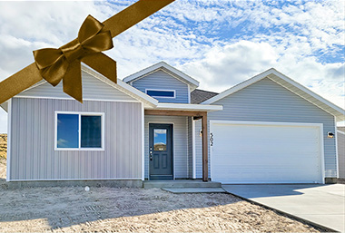 grey blue and white trimmed house with porch and vaulted entryway. A blue sky with white clouds is behind and a brown ribbon is across the corner of the photo